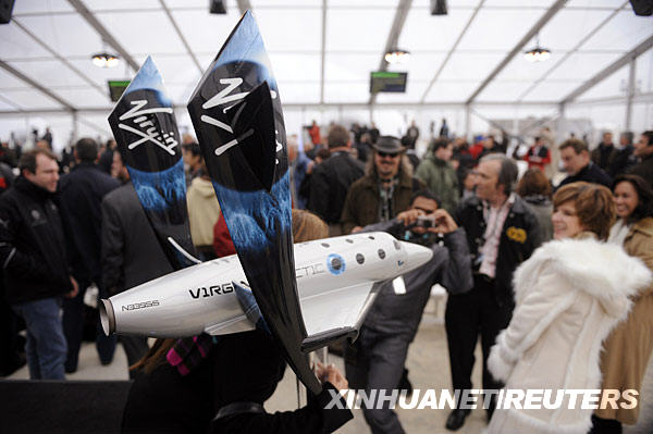 12月7日，在美国加利福尼亚州莫哈韦沙漠的航空航天机场，人们在新闻发布会会场拍摄“太空船二号”的模型。新华社/路透